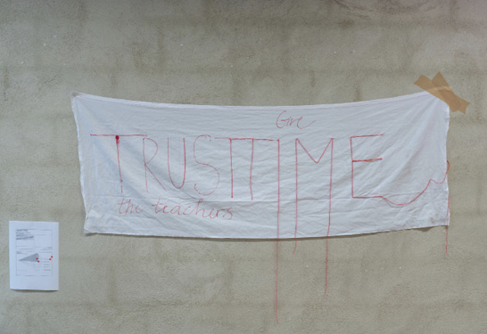 <p><strong>FAST45 Futures Archive – Artefact #12 – <em>Trust Time</em></strong></p><p><em>“Give time, trust the teachers,” reads the red text on white cotton. It is a banner to remind us that time is needed in the present to think about the future of HAE and while shaping it, decision-makers should not forget to trust the educational staff.</em></p>
