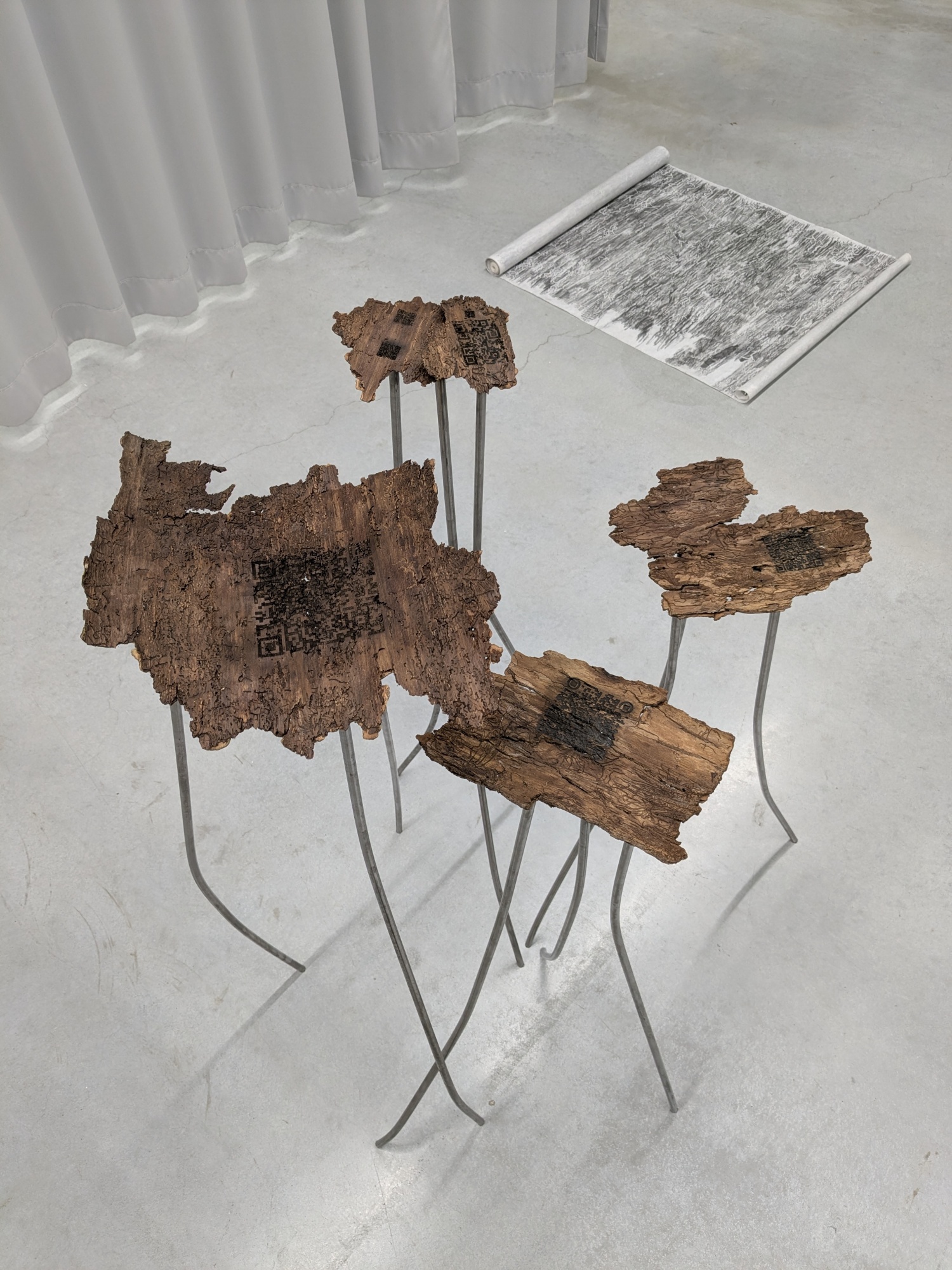 <p>Fig. 7: Lise Van den Broucke, <em>&ldquo;Root Reader QR&rdquo;, unreadable brain cloud of floating data, steel and laser-printed bark, part of an installation</em>,<em> </em>2025-2026. Photo by Anneleen Swillen.</p>